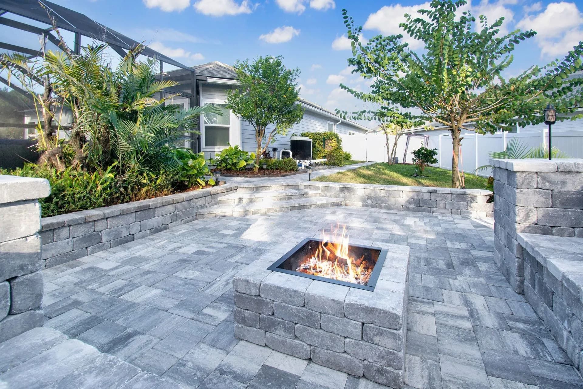 St. Johns Pavers firepit with gray pavers and seating walls in a landscaped backyard in St. Johns, F