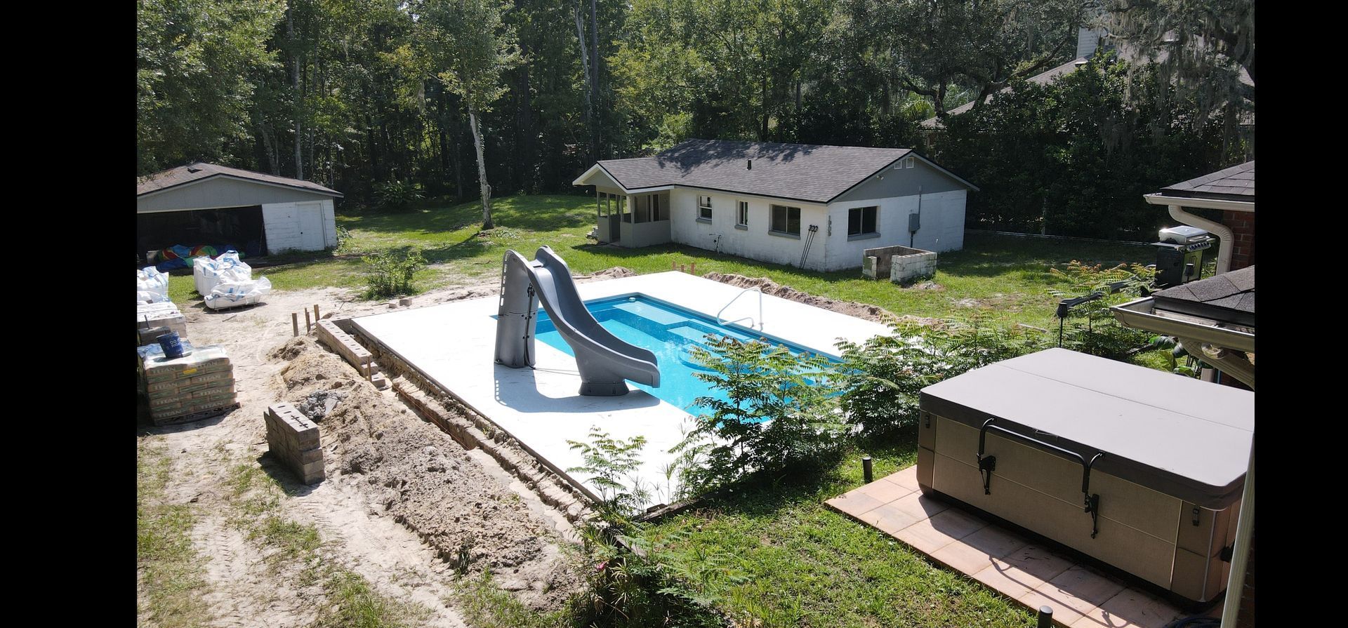 An aerial view of a swimming pool with a slide and a house in the background.