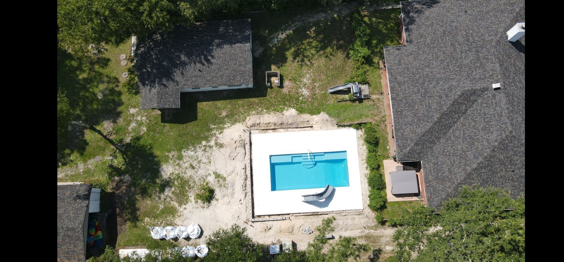 An aerial view of a swimming pool in the backyard of a house.