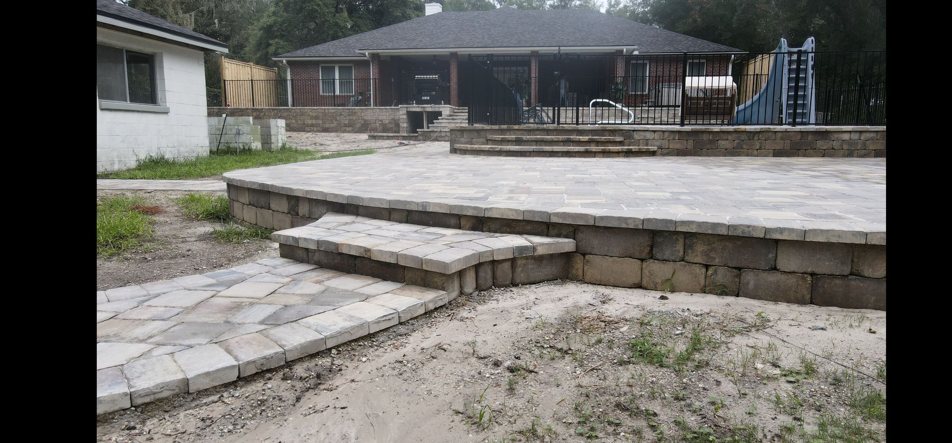 A stone wall with stairs leading up to a garden.