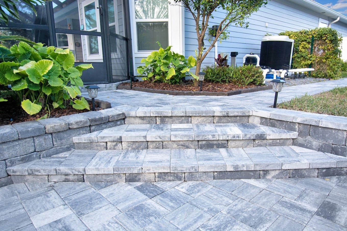 A brick walkway with a stone wall in the background