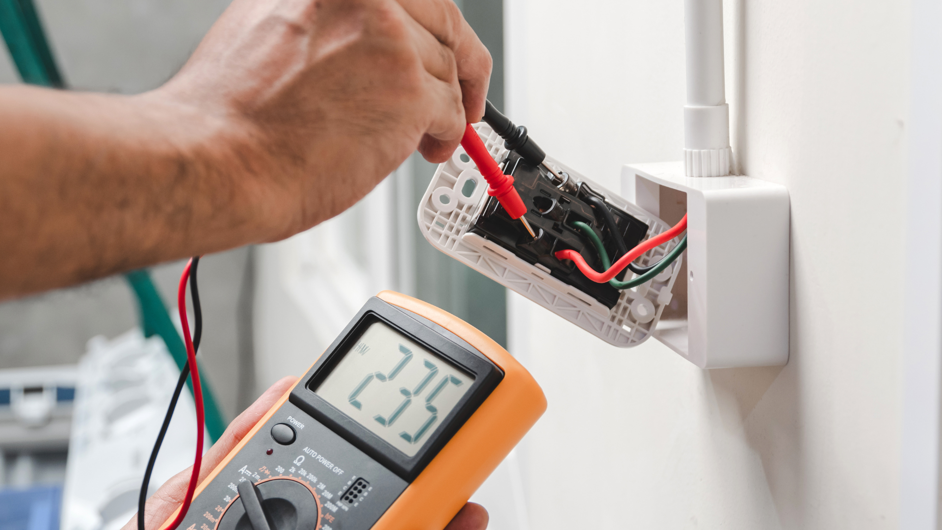 Person testing an electrical outlet with a multimeter, showing 235 volts.
