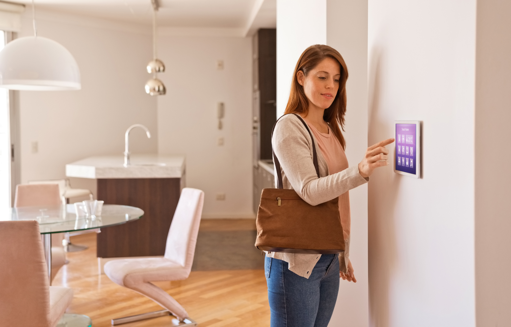 Woman with purse touches smart home control panel on wall in modern home.