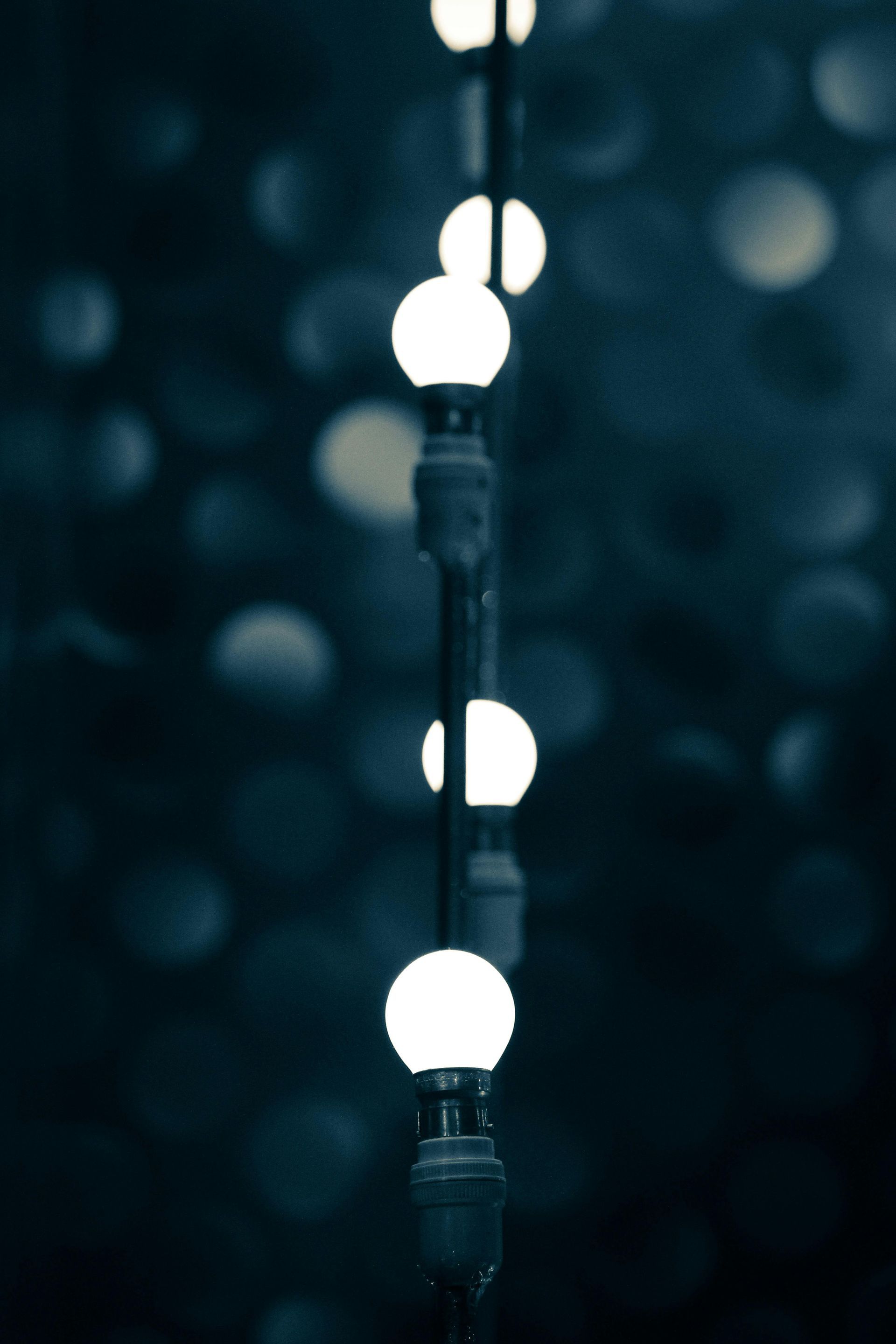 String of glowing white orbs on a dark background, suggesting a nighttime or indoor setting.