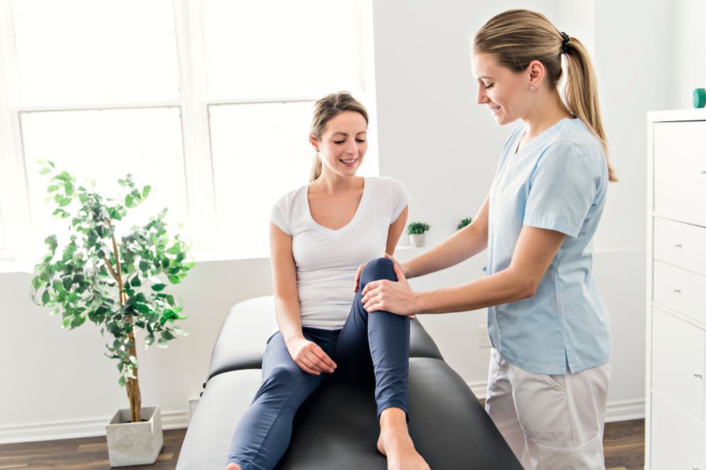 A Woman is Sitting on a Bed While a Nurse Examines Her Leg — PhysioCare Townsville In Thuringowa Central, QLD