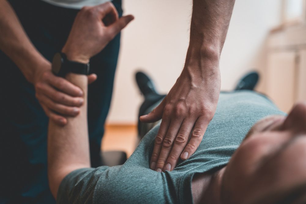 A Man is Laying on the Floor Getting a Massage From Another Man — PhysioCare Townsville In  Townsville, QLD