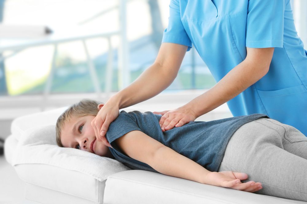 A Young Boy is Laying on a Bed Getting a Massage From a Nurse — PhysioCare Townsville In  Townsville, QLD