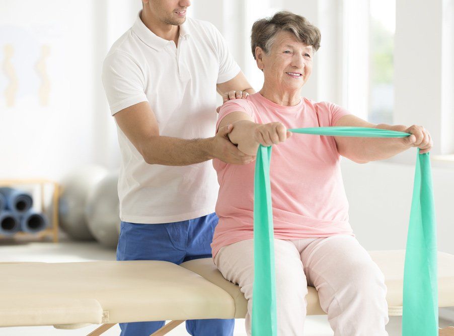 A Man is Helping an Elderly Woman With a Resistance Band — PhysioCare Townsville In Thuringowa Central, QLD