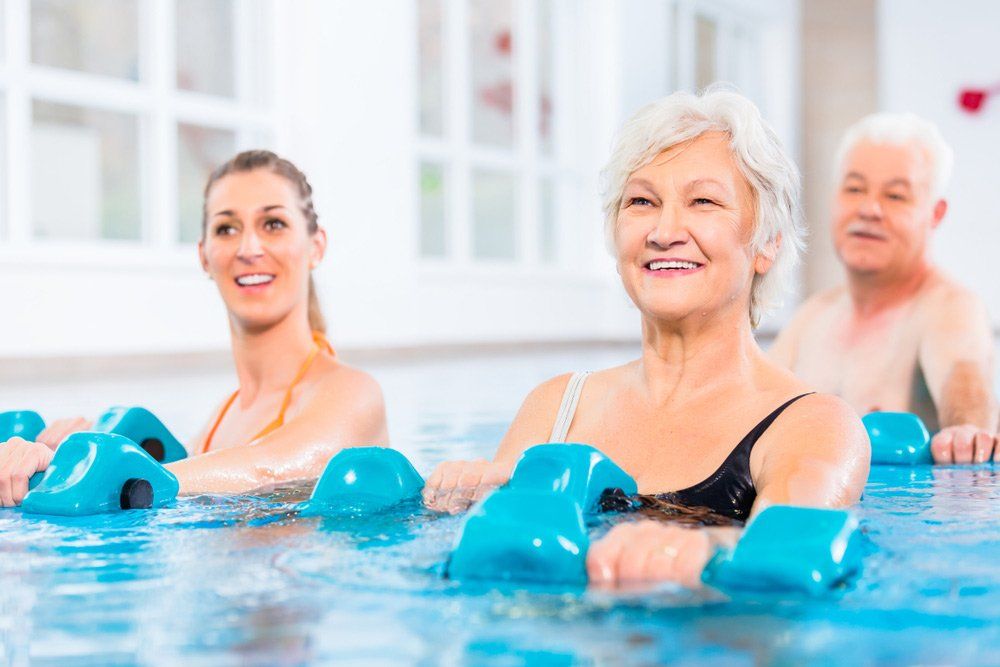 People Young and Senior in Water Gymnastics Physiotherapy With Dumbbells — PhysioCare Townsville In Thuringowa Central, QLD