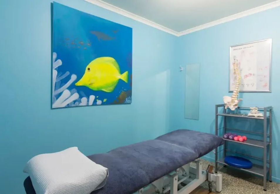 A Blue Room With a Bed and a Painting of a Fish on the Wall — PhysioCare Townsville In Deeragun, QLD