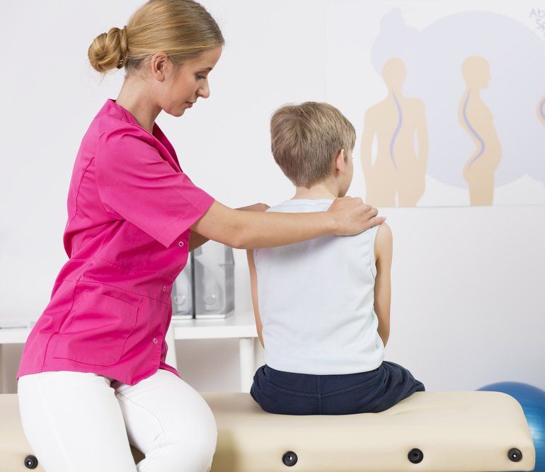 PhysiotHerapist Correcting Body Posture of a Small Boy — PhysioCare Townsville In Thuringowa Central, QLD