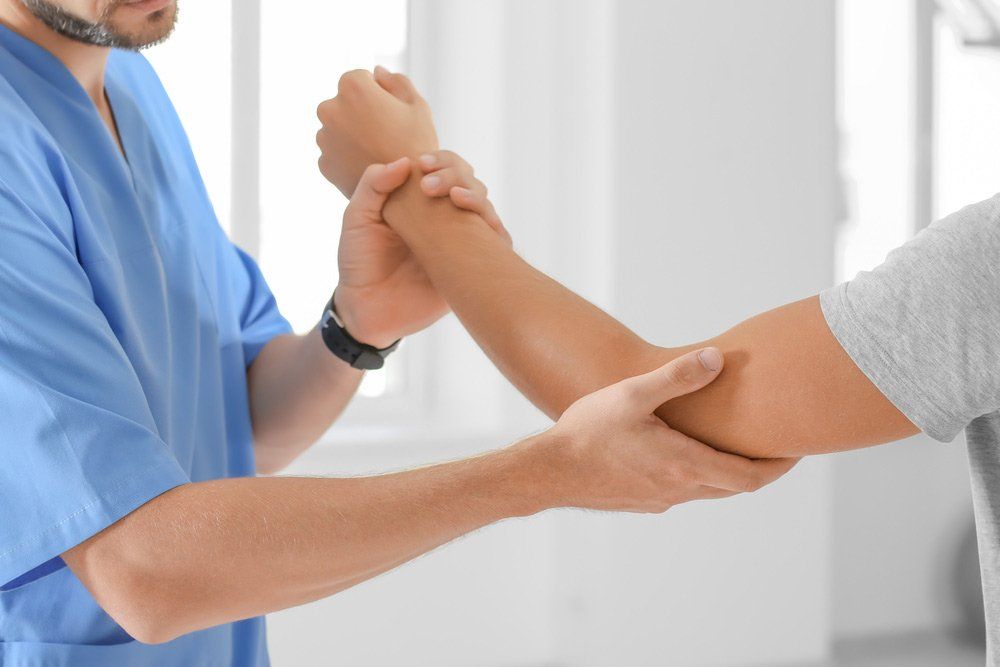 Physiotherapist Working With Male Arm Patient in Clinic — PhysioCare Townsville In Thuringowa Central, QLD
