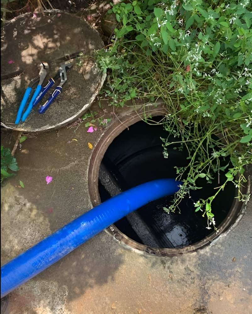 A Blue Hose is Coming Out of a Manhole Cover — Glenview Septic & Liquid Waste Removal In Narangba, QLD