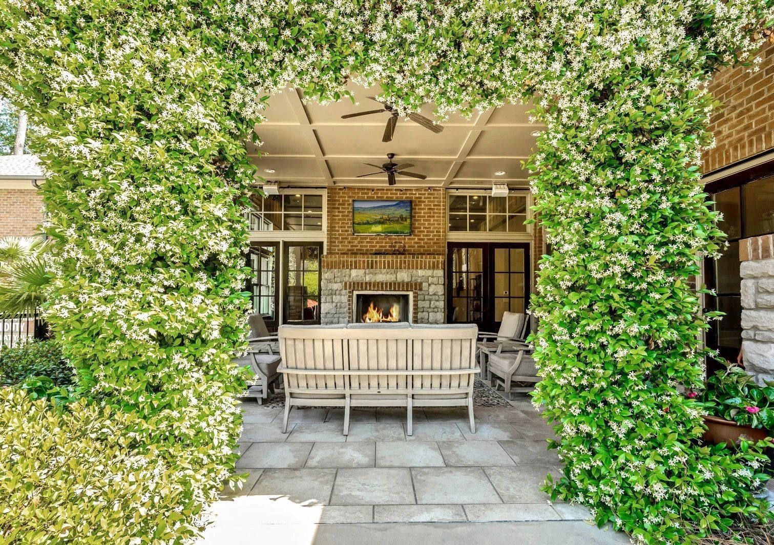 Covered patio with stone flooring, white bench, fireplace, and ivy-framed opening  at Arcadia's Edge Apartments in Columbia, SC
