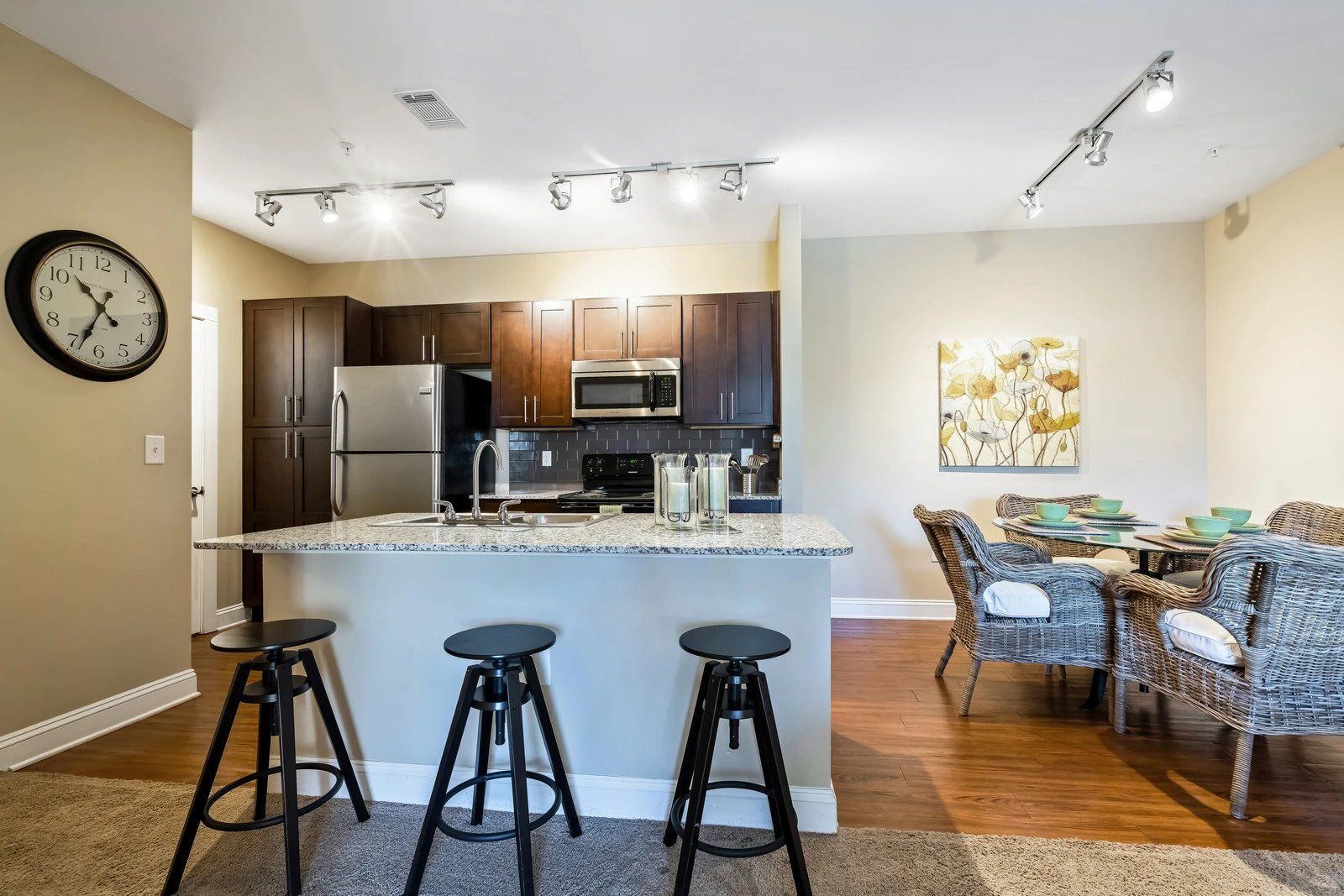 Open kitchen and dining area with granite island, bar stools, stainless appliances, and patterned chairs  at Arcadia's Edge Apartments in Columbia, SC
