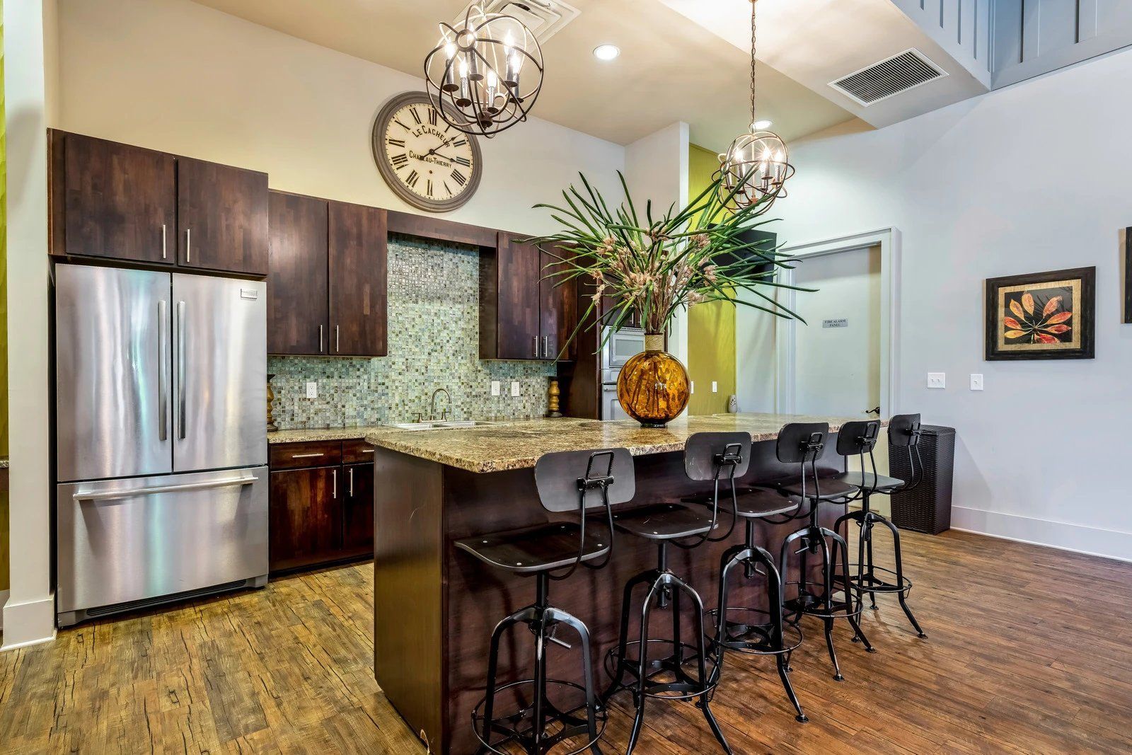 Modern kitchen with stainless steel fridge, island seating, dark wood cabinets, and pendant lights  at Arcadia's Edge Apartments in Columbia, SC