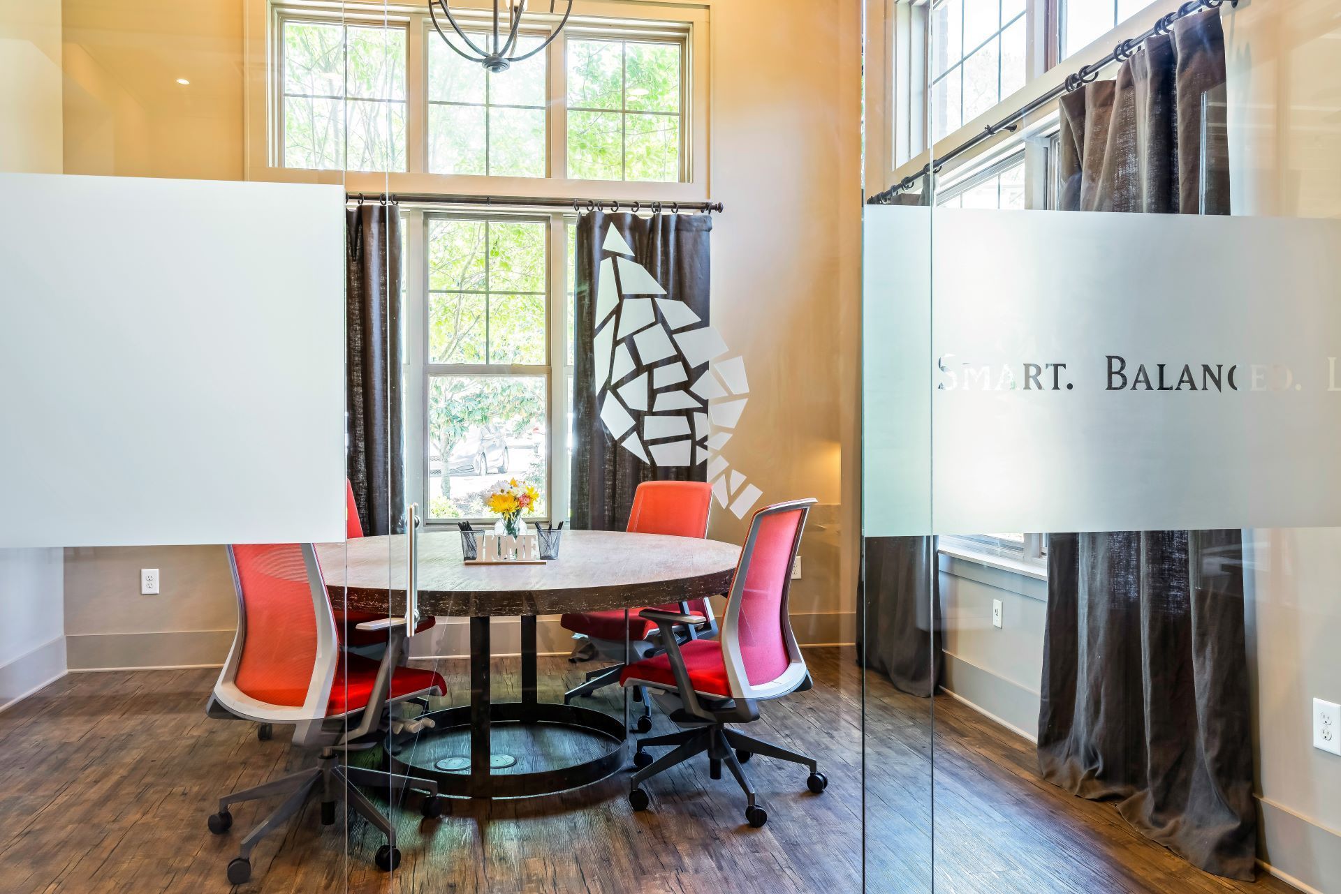 Modern office conference room with round table, orange chairs, and frosted glass walls  at Arcadia's Edge Apartments in Columbia, SC