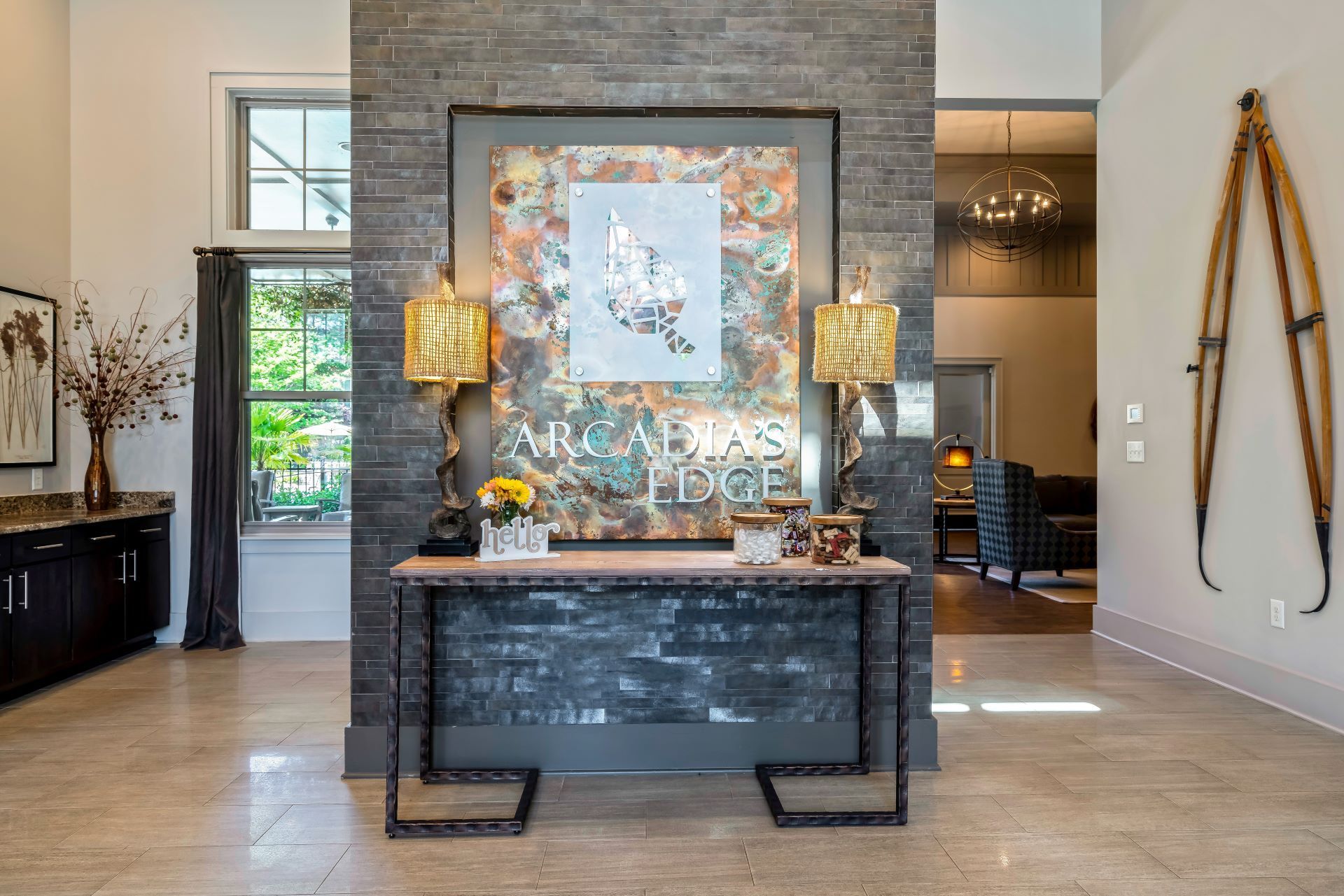 Modern lobby with stone feature wall, console table, wall art, and hanging decor in a bright interior  at Arcadia's Edge Apartments in Columbia, SC