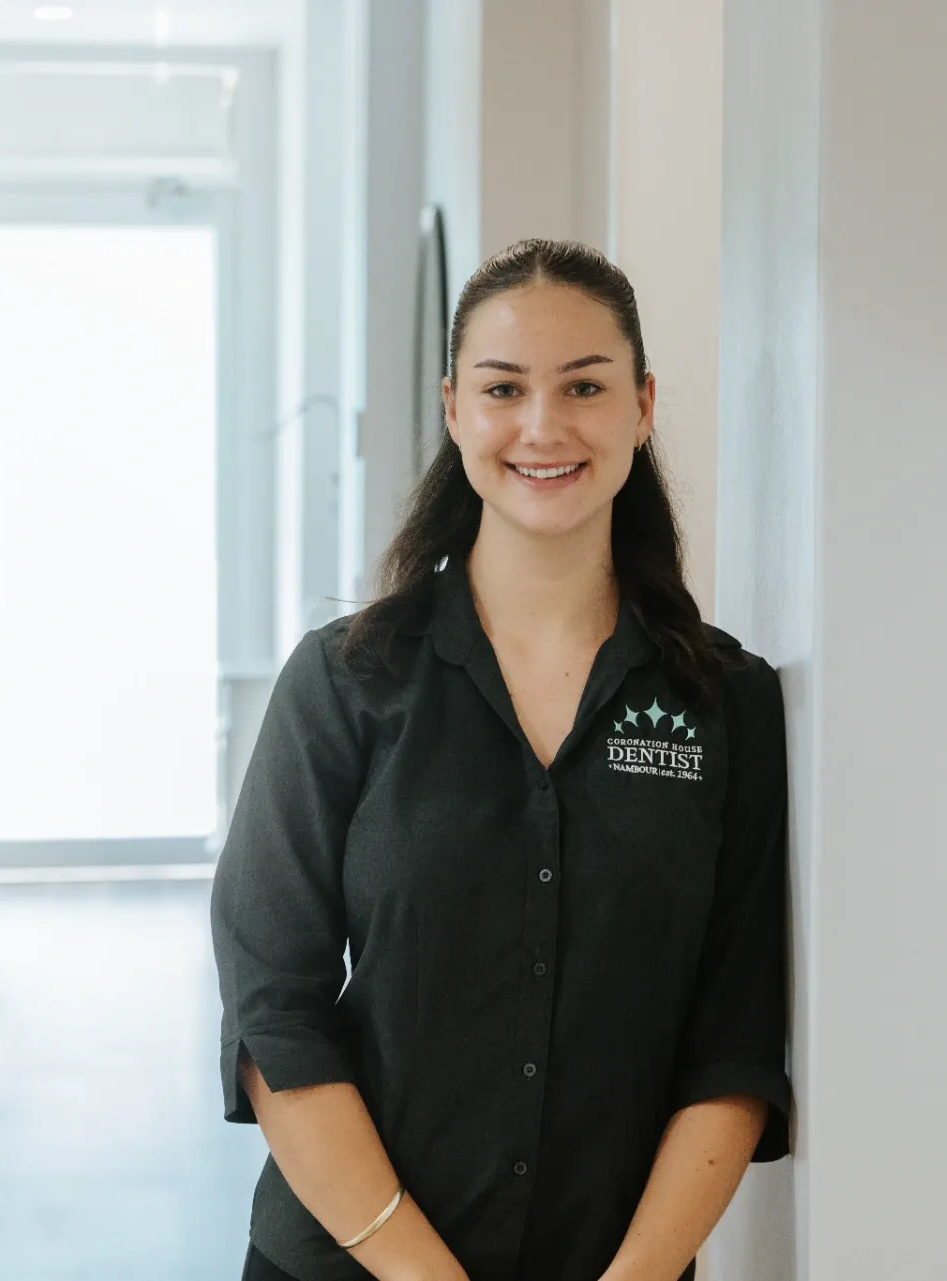 Smiling woman in a black shirt standing in a bright hallway