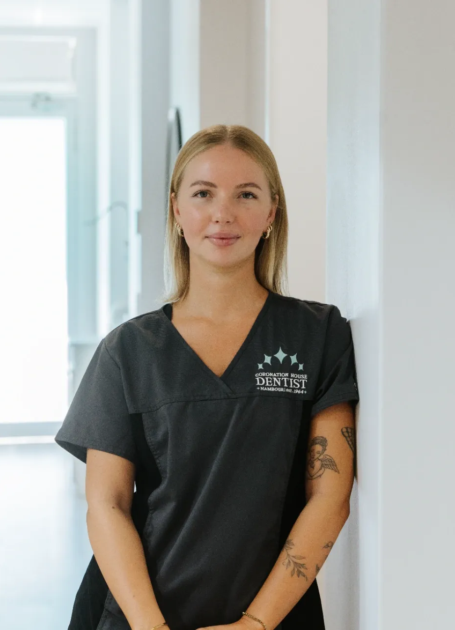 Woman in dark scrubs standing in a bright hallway