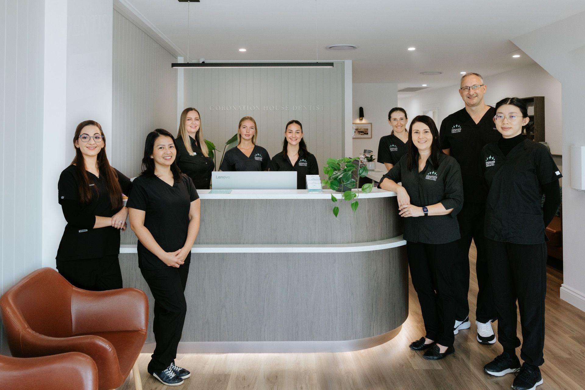 Team of people standing behind a modern reception desk in a bright office lobby — Coronation House Dentist in Nambour, QLD