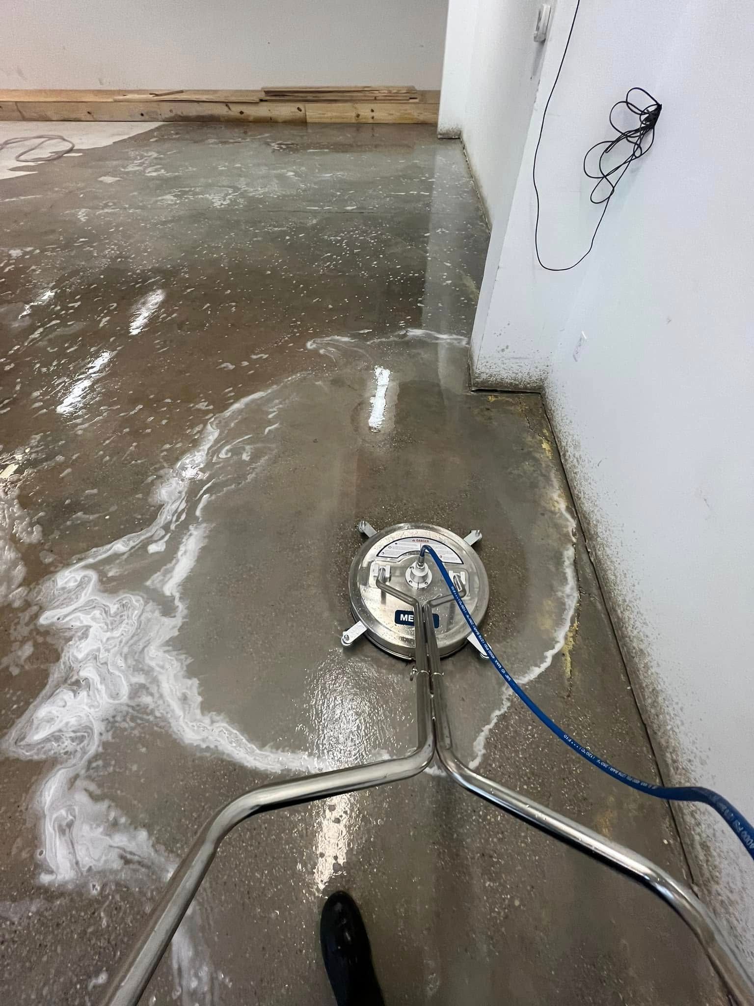 Wet concrete floor with a floor grinder or polisher and power cord in an unfinished room