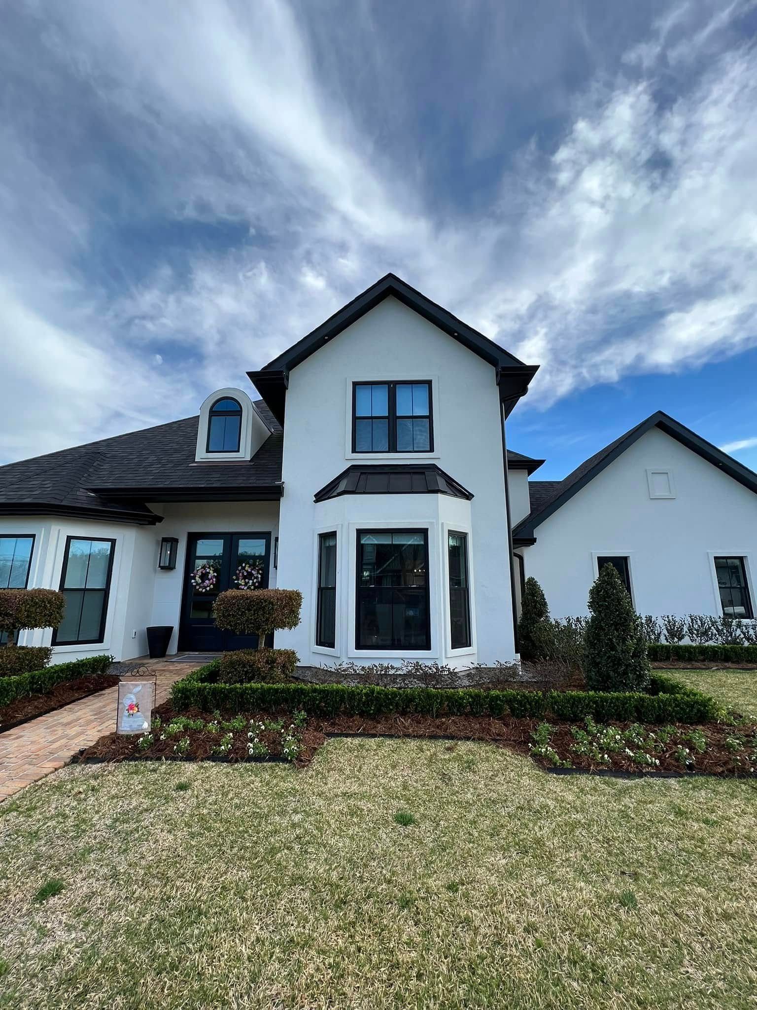 White two-story house exterior with dark roof, blue-trimmed windows, and front entry