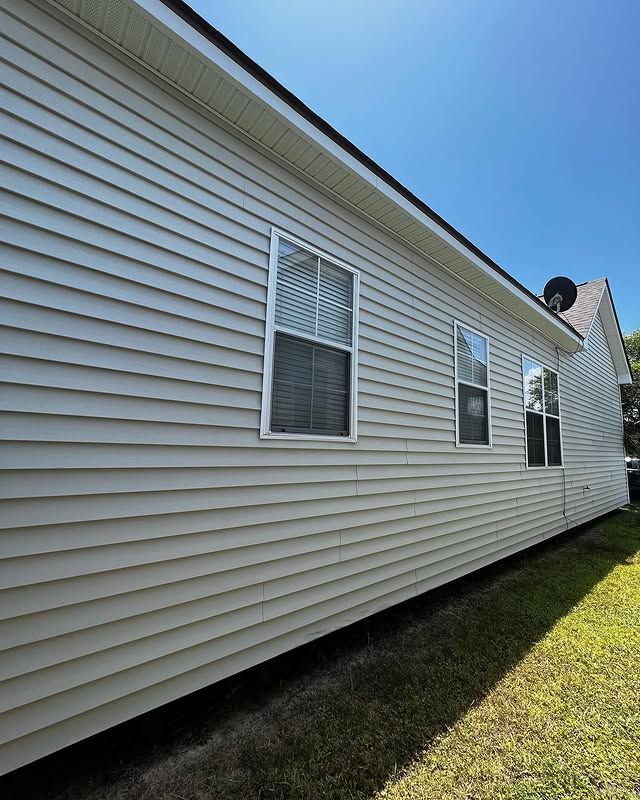 Suburban house roofs with beige siding and dark shingles against a blue sky