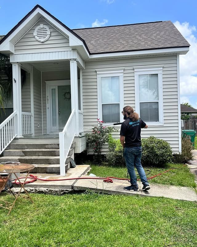 Person pressure-washing a wooden deck with bright sunlight and water spray visible