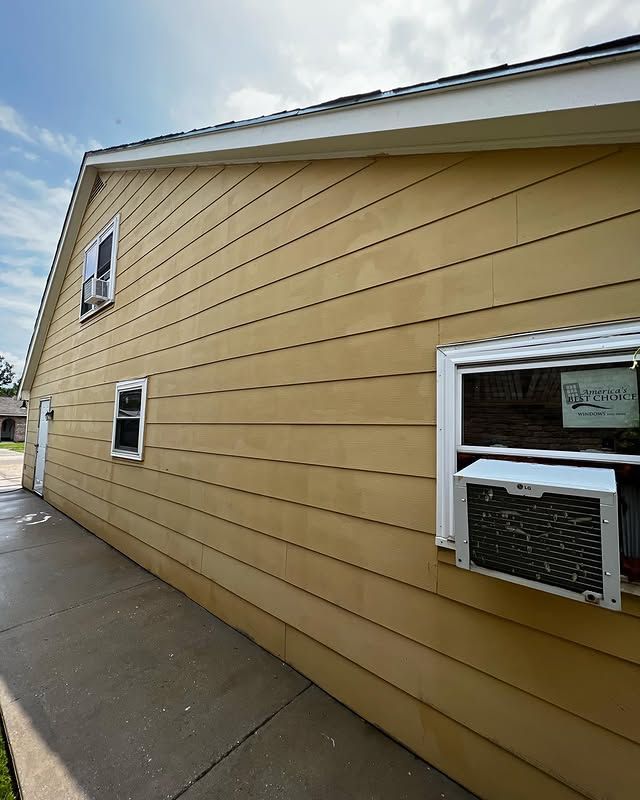 Close-up of a brick gable under beige siding and dark roof trim against a cloudy sky