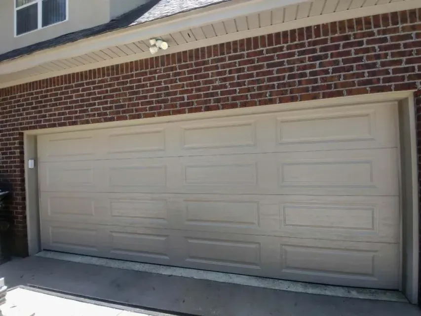 Tan garage door in front of a brick building.