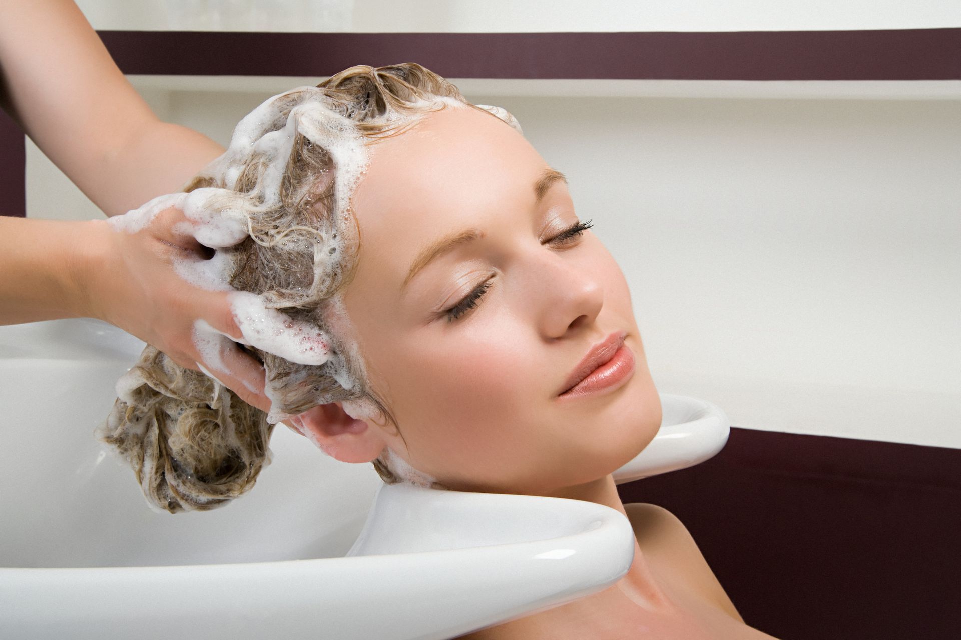 Una donna si sta lavando i capelli nel lavandino di un salone.