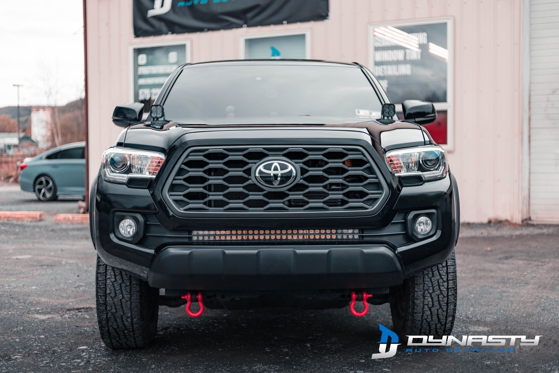 A black toyota tacoma truck is parked in front of a building.
