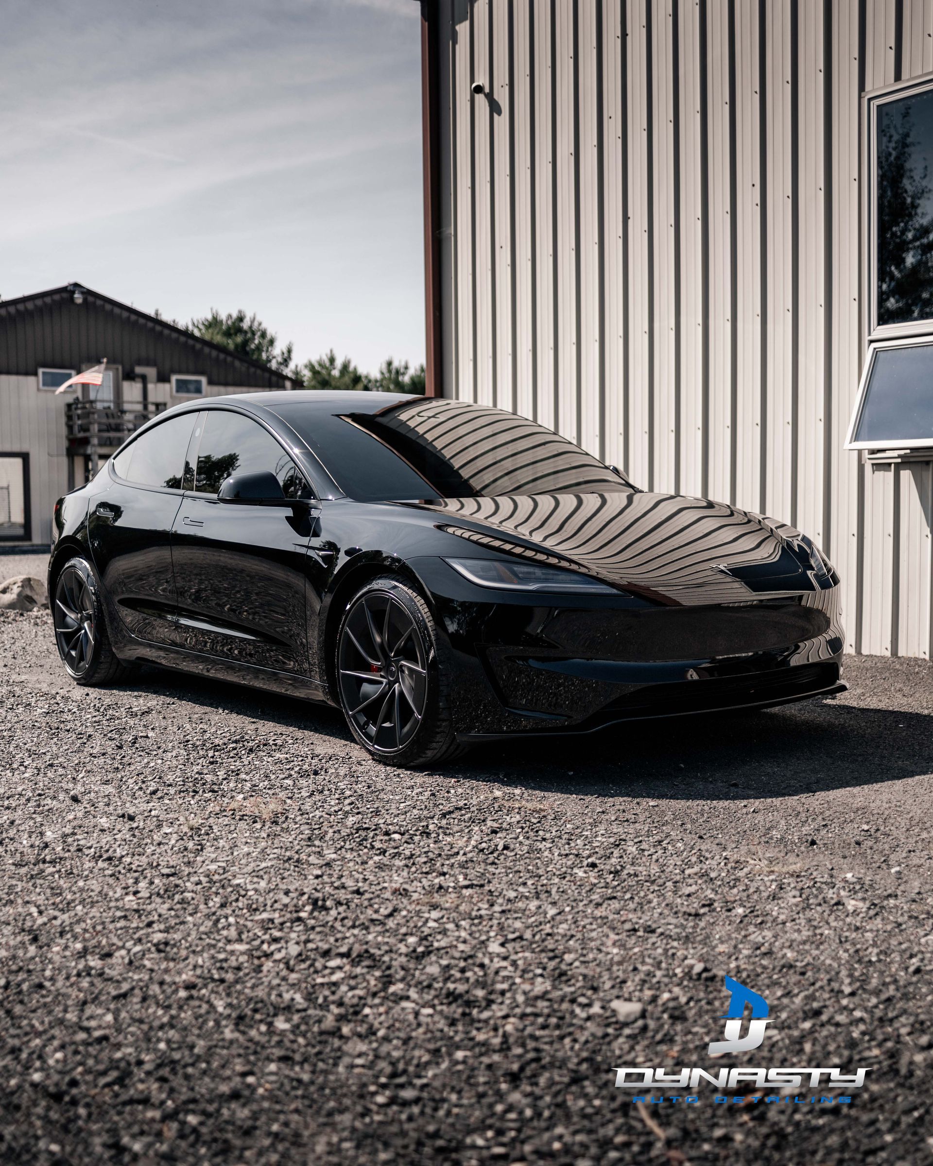 A black tesla model 3 is parked in front of a building.
