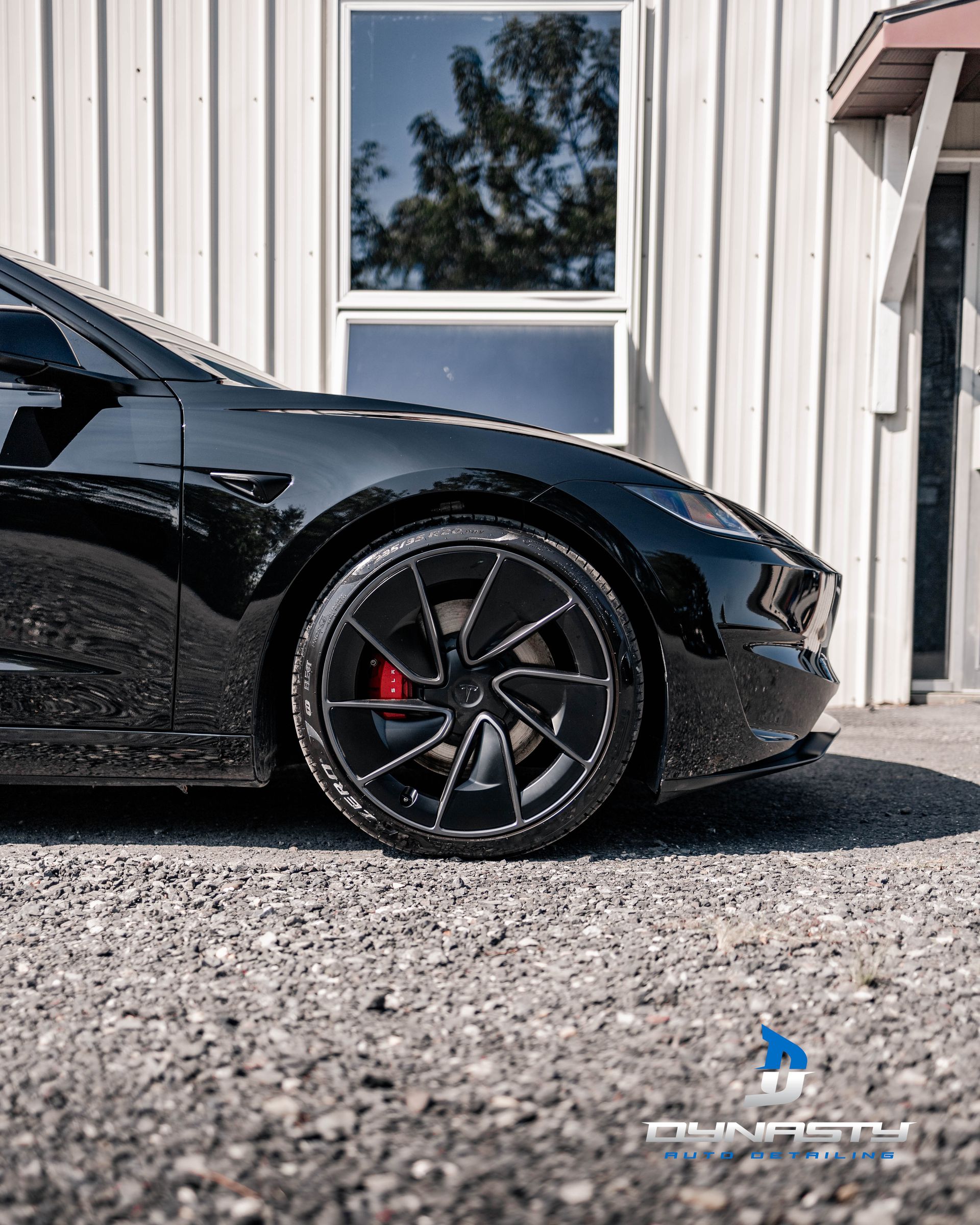 A black tesla model 3 is parked in front of a building.