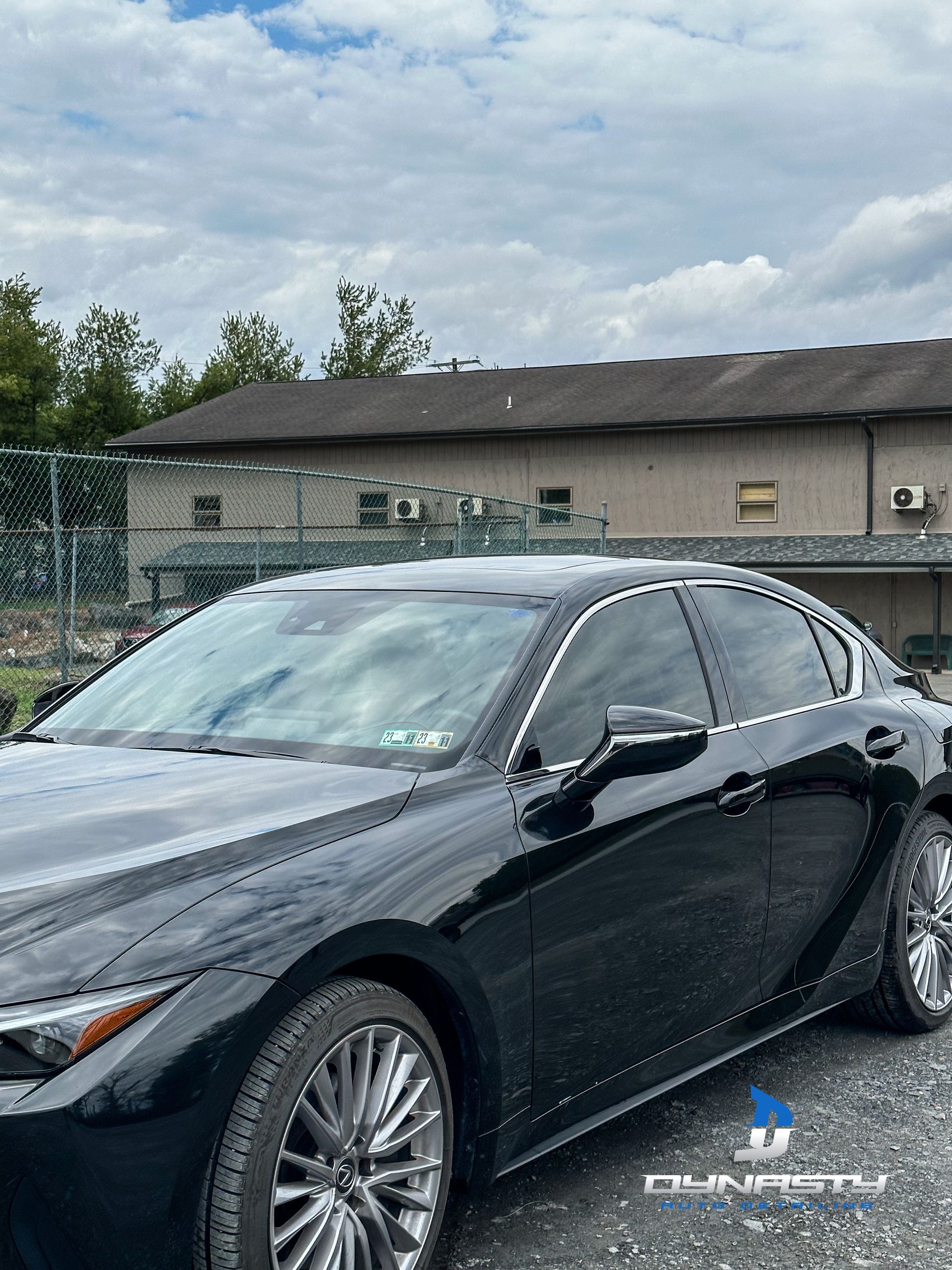 Black Lexus car parked outside a building on a cloudy day.