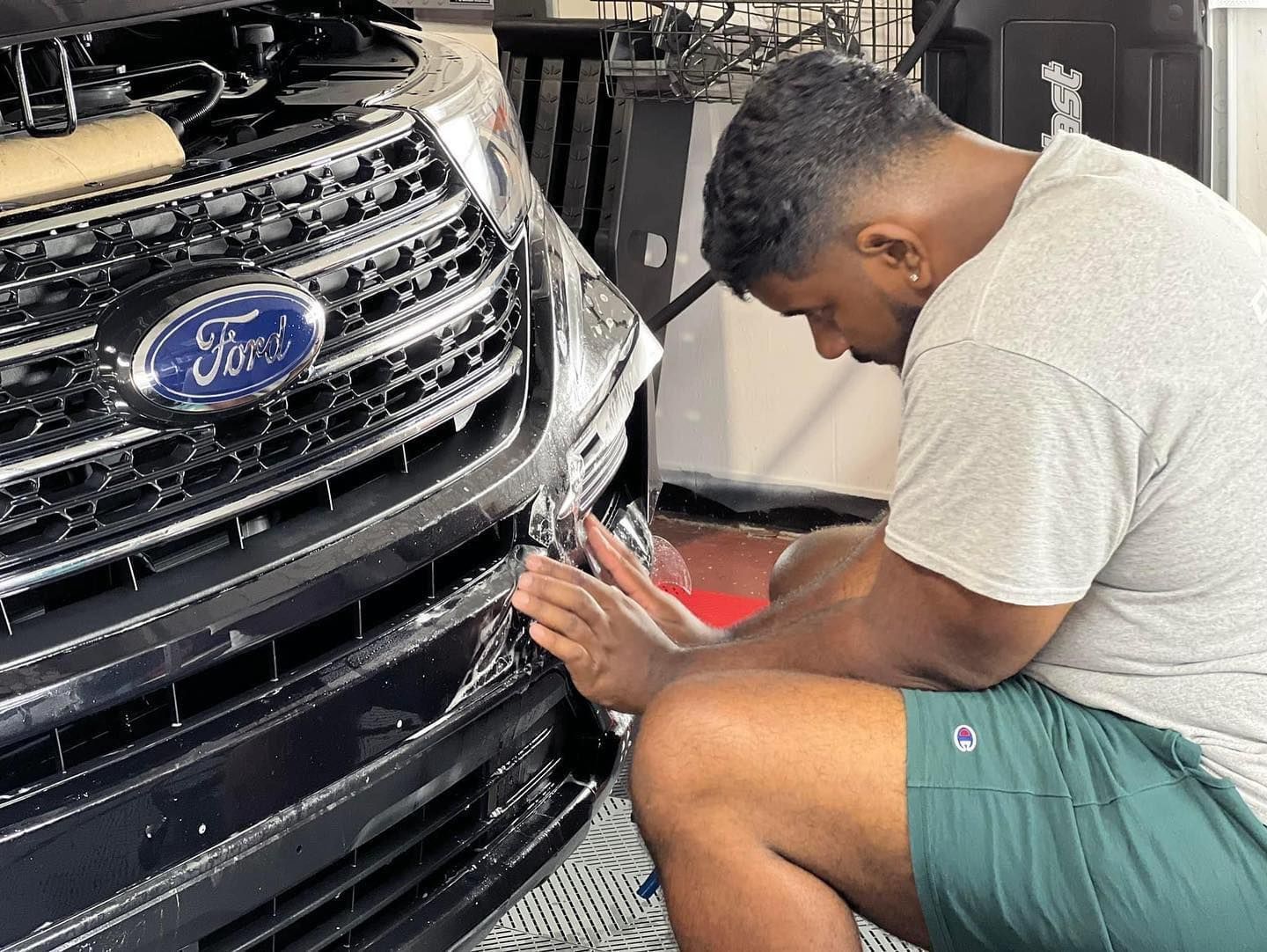 A man is applying a protective film to the headlights of a mercedes benz.