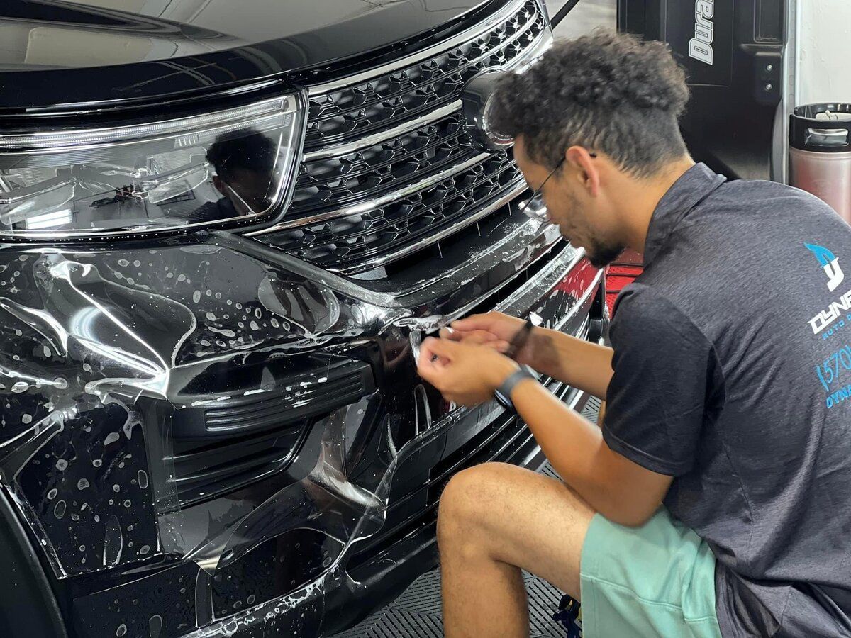 A person is applying protective film to the hood of a car.