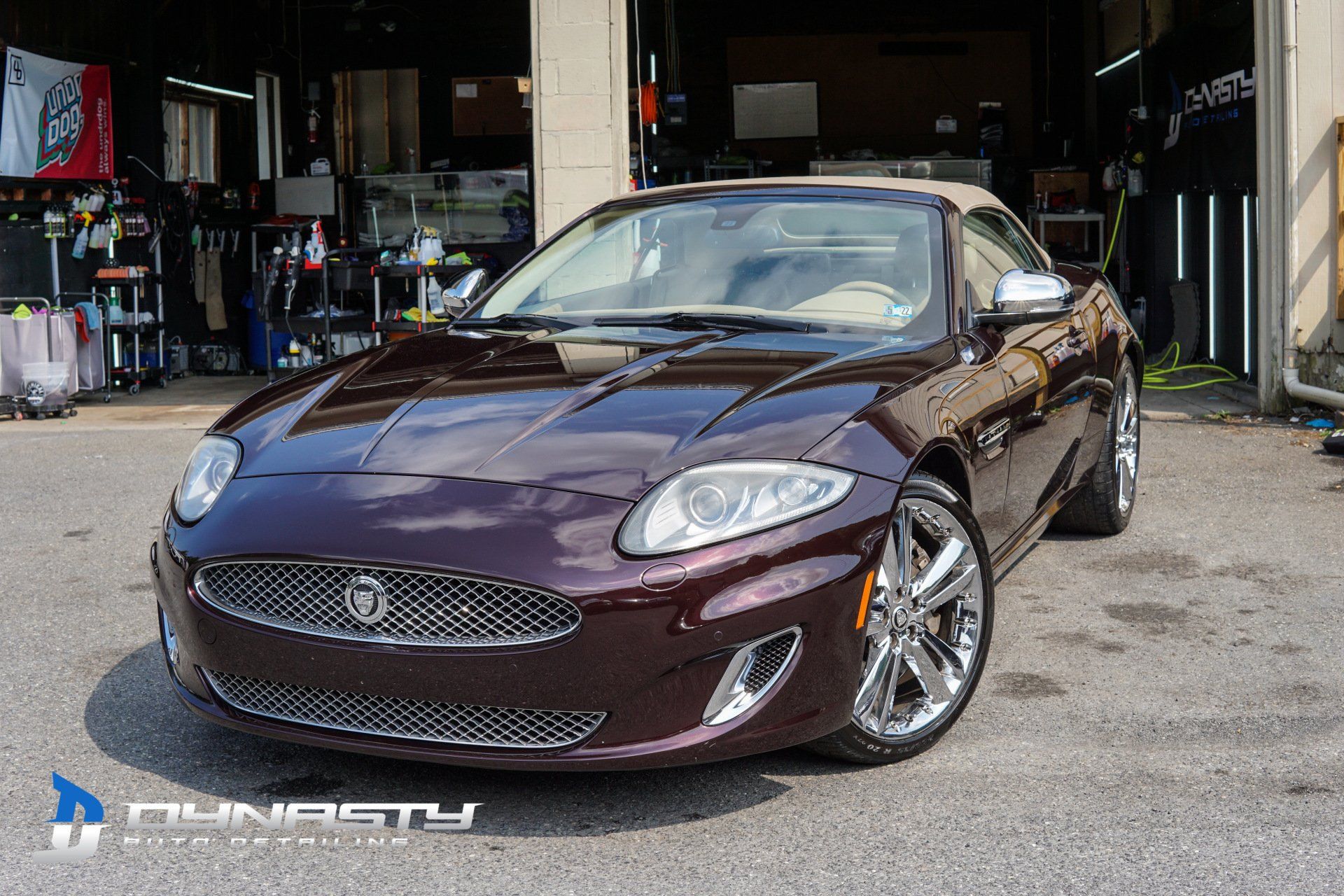 Ceramic Coating - A maroon Jaguar sports car is parked in front of a garage.