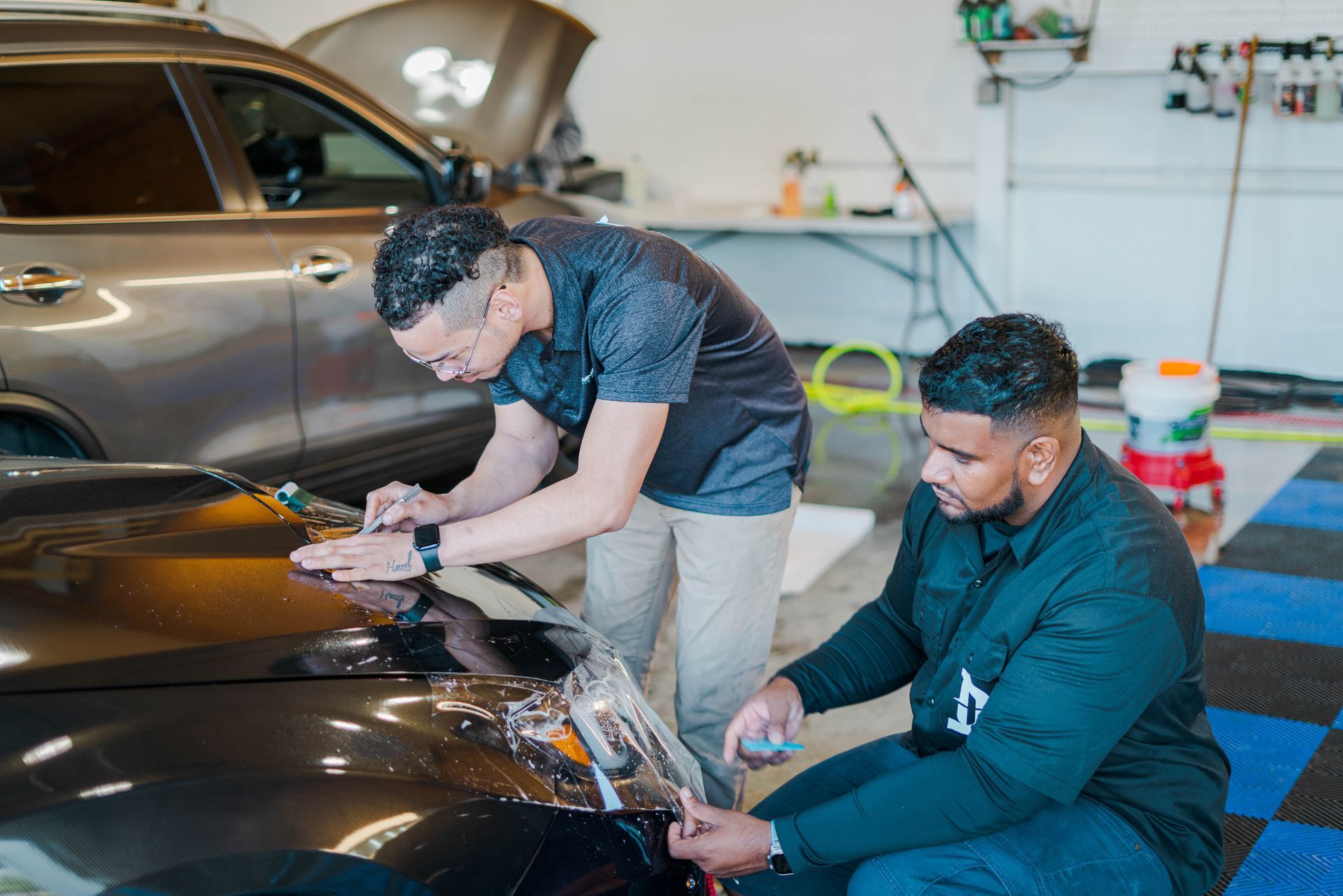 A man is applying a protective film to the side mirror of a car.