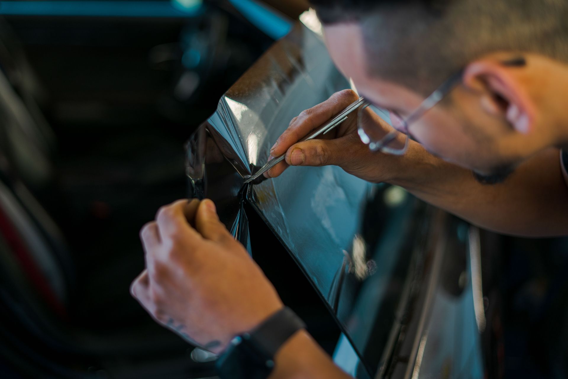 A man is cleaning the windshield of a car with a blue towel.