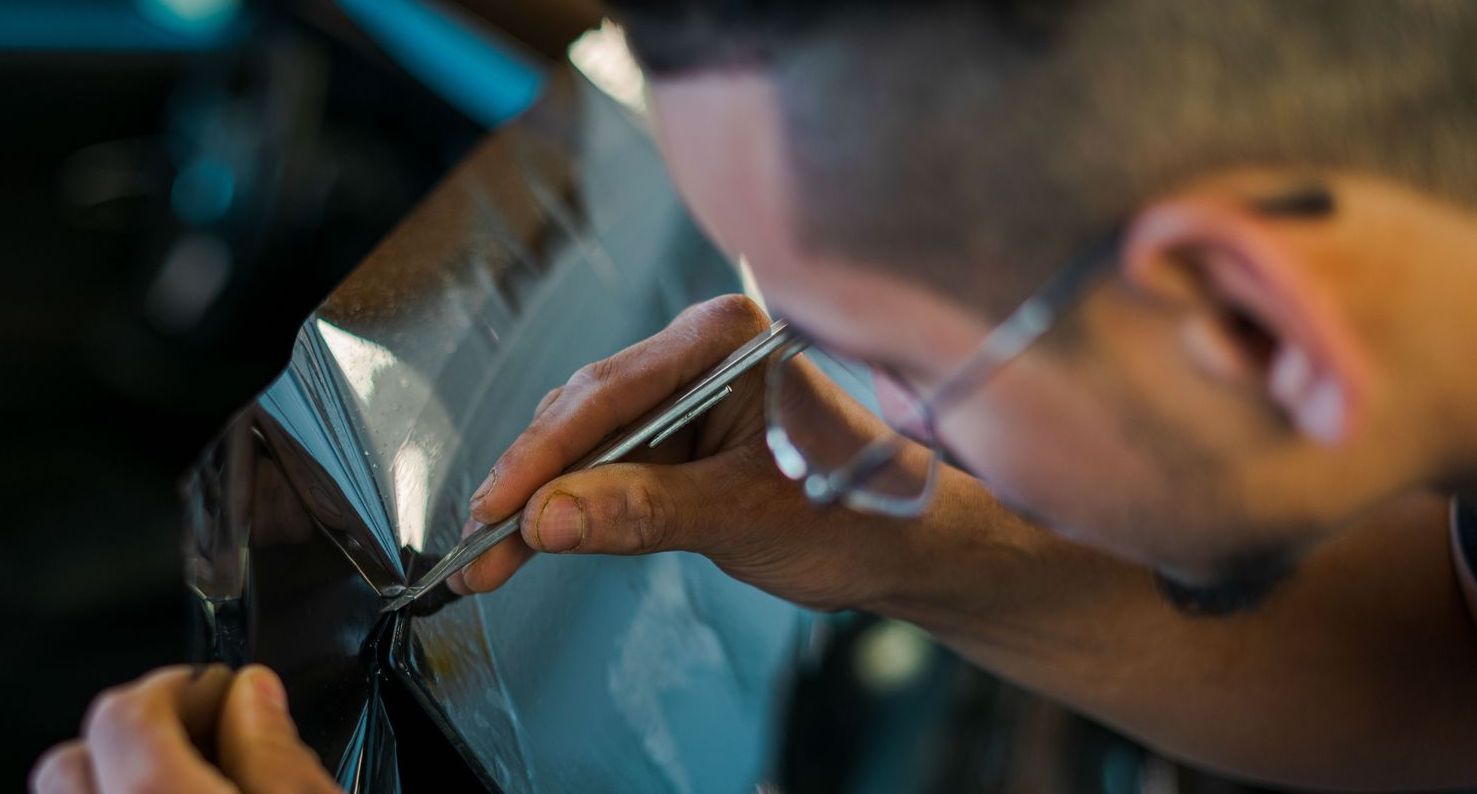 A man is cutting a piece of plastic with a pair of scissors.