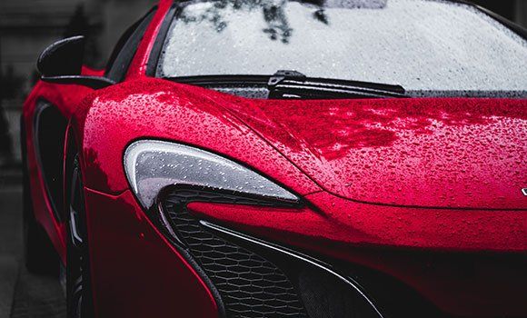 Red sports car parked; wet from rain.
