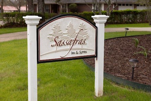 “Sassafras” neighborhood sign on white posts beside a grassy residential lawn