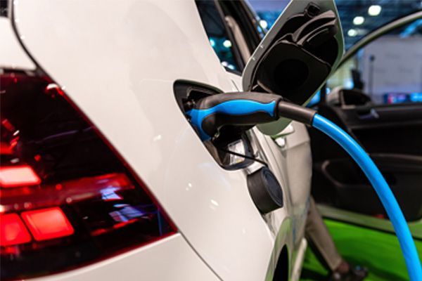 Blue charging cable plugged into a white electric car at a charging station