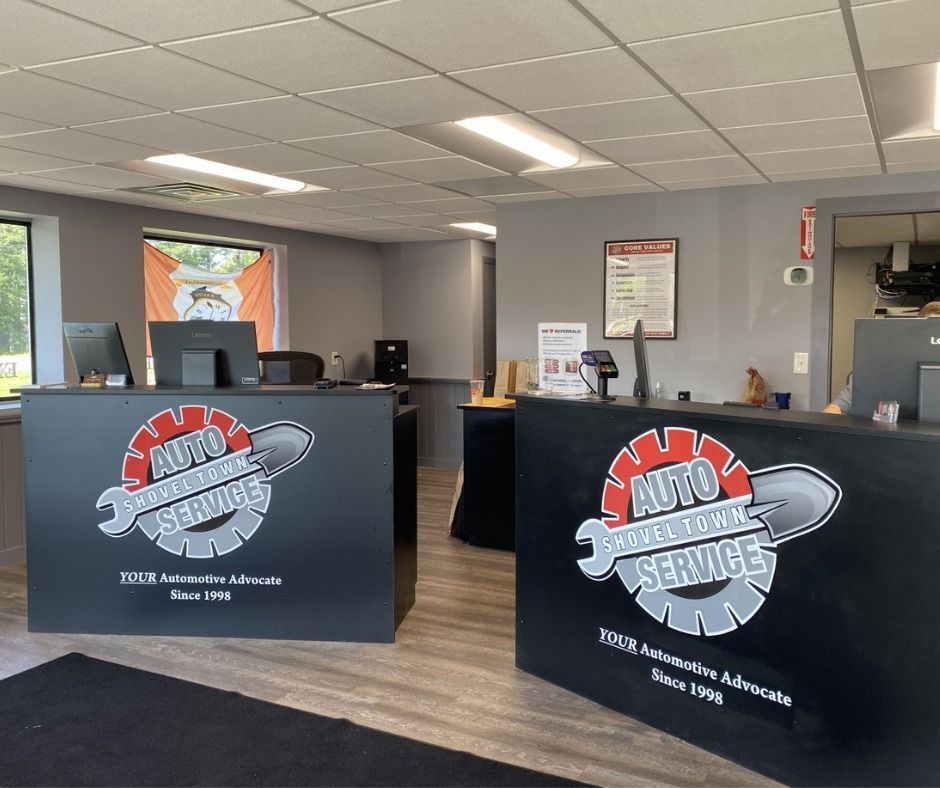 Auto service lobby with two black counters, ceiling lights, and a service desk sign in a gray waiting area