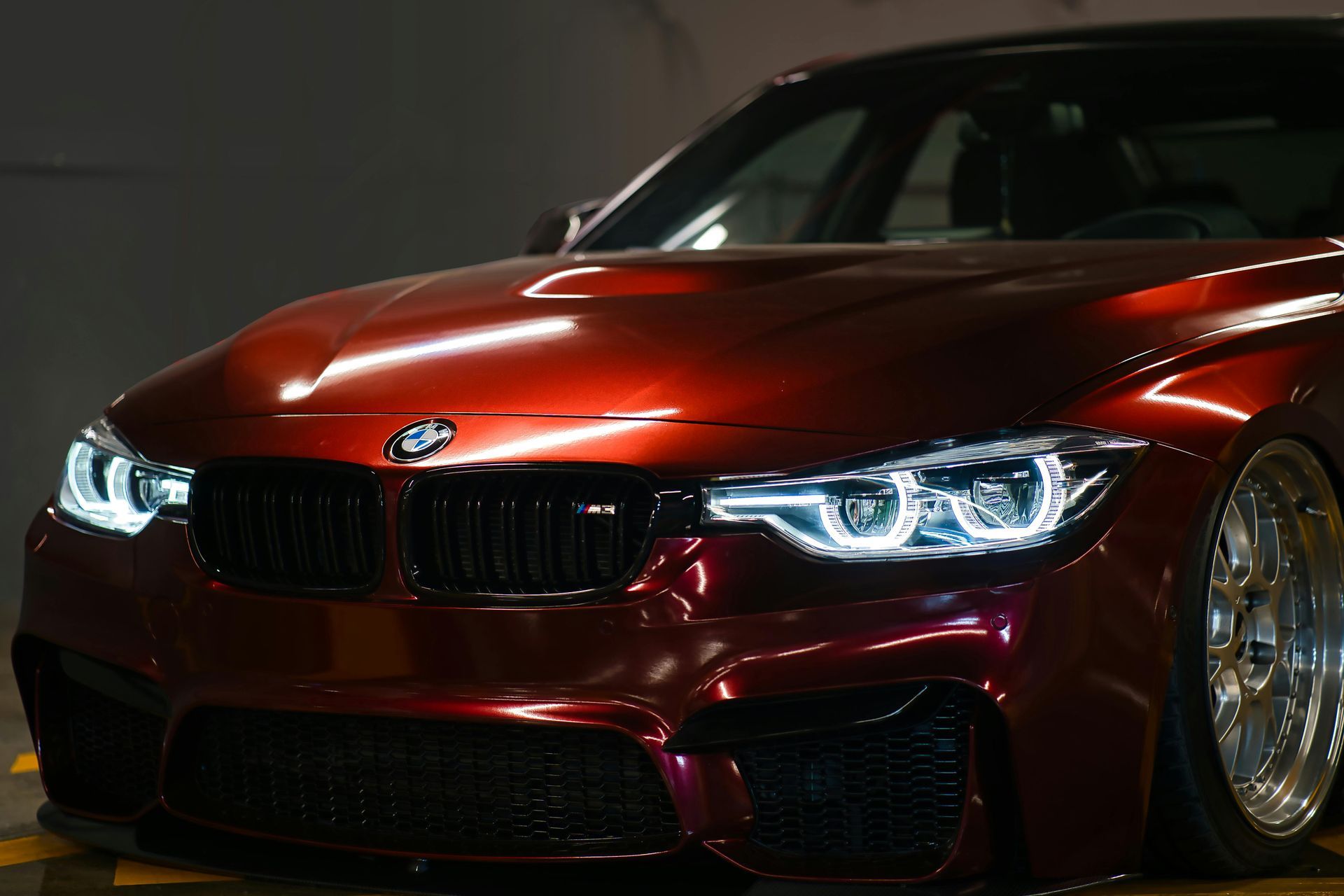 Red sports coupe with bright headlights and glossy paint in a dark setting