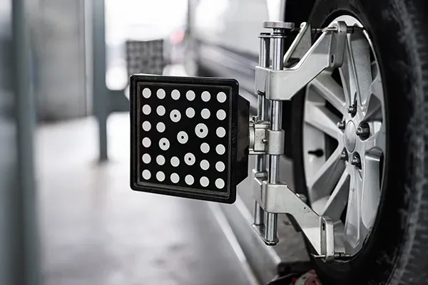 Close-up of a car wheel alignment sensor mounted on a vehicle in a garage