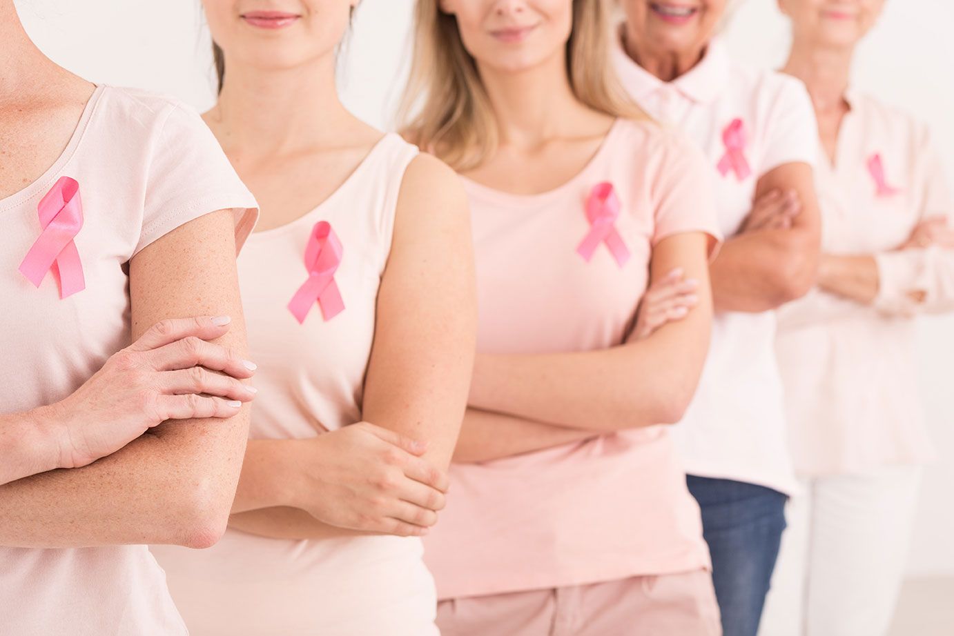 Group of people in white and pink shirts wearing pink breast cancer awareness ribbons
