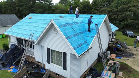 Roofing crew installing protective underlayment on a residential home before new shingles